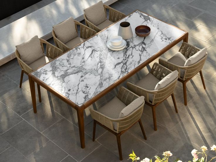 a dining table with chairs and a vase on it in the middle of a patio