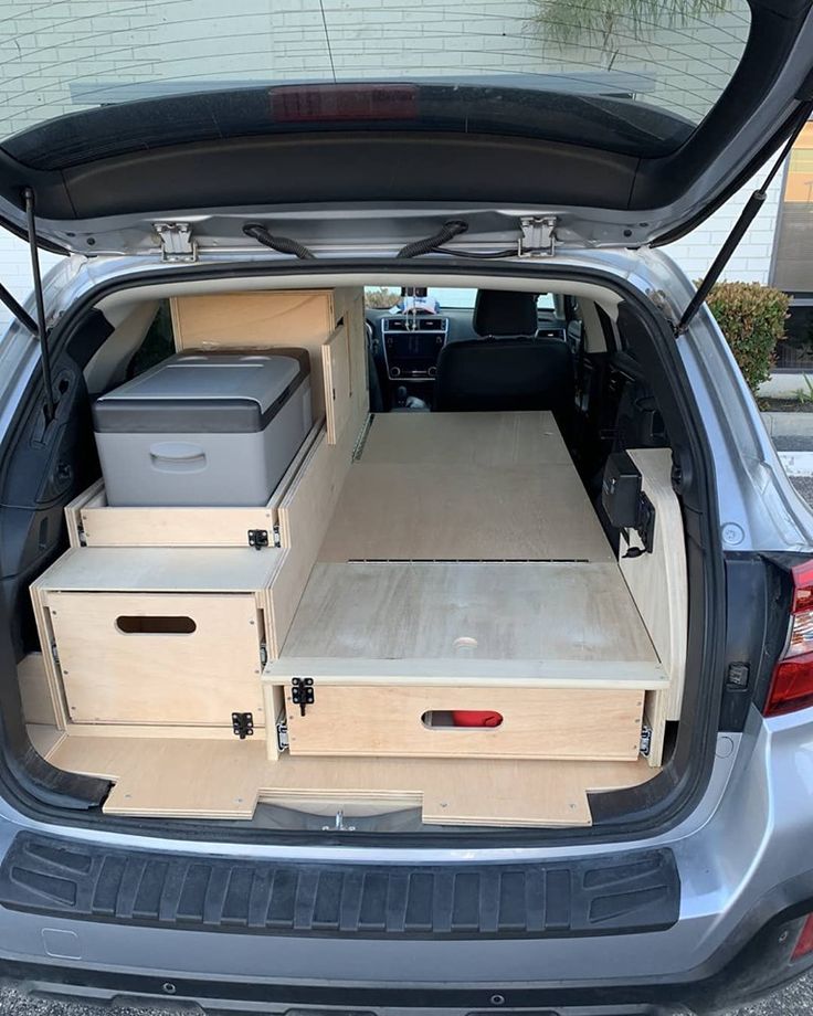 the back end of a car with its trunk open and storage boxes in the cargo area