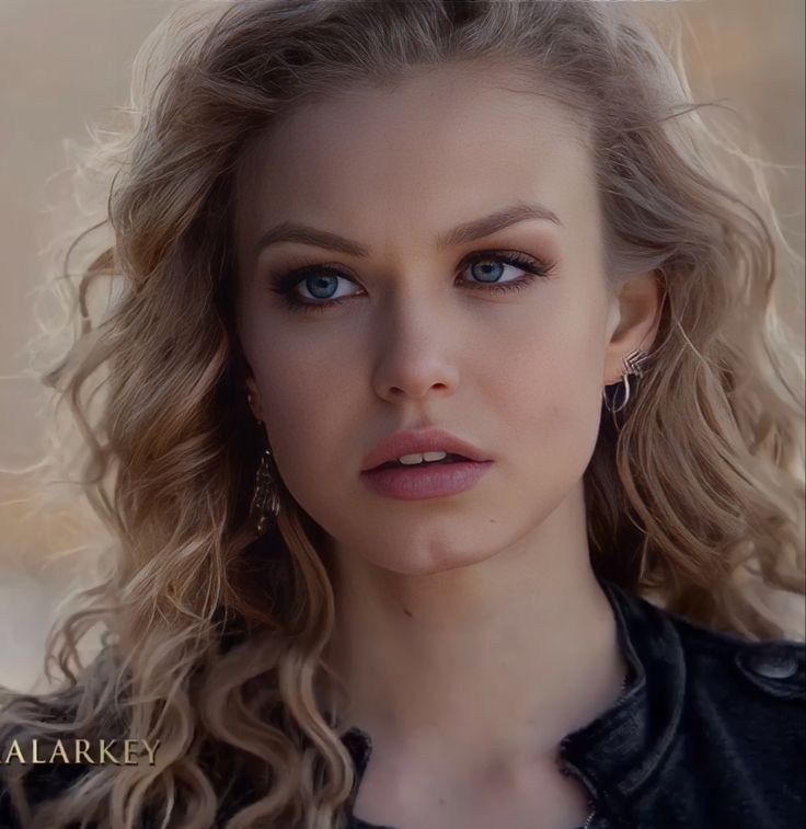 a woman with blonde hair and blue eyes is looking at the camera while wearing earrings