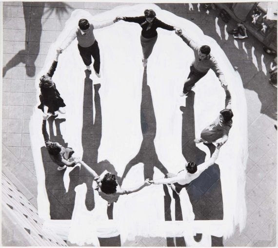 an aerial view of people holding hands in the shape of a circle on a skateboard ramp