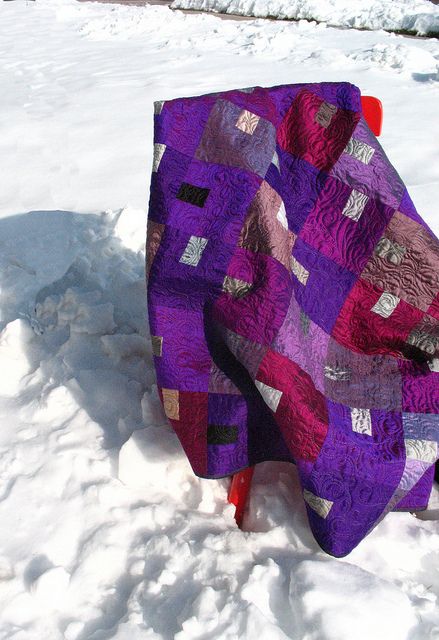 a purple quilt sitting on top of snow covered ground