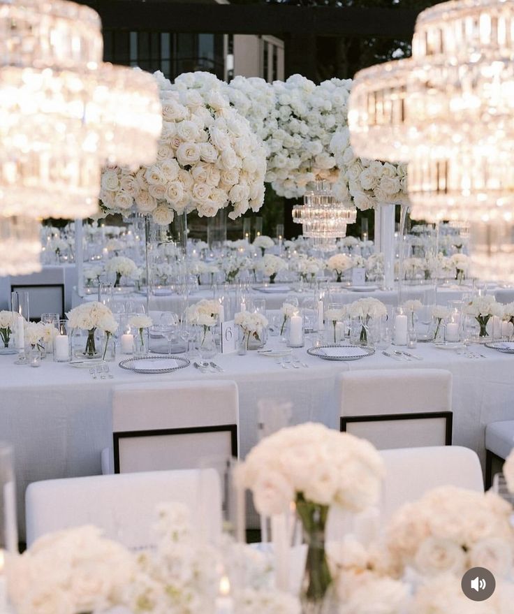 the tables are set with white flowers and crystal chandeliers for an elegant wedding reception