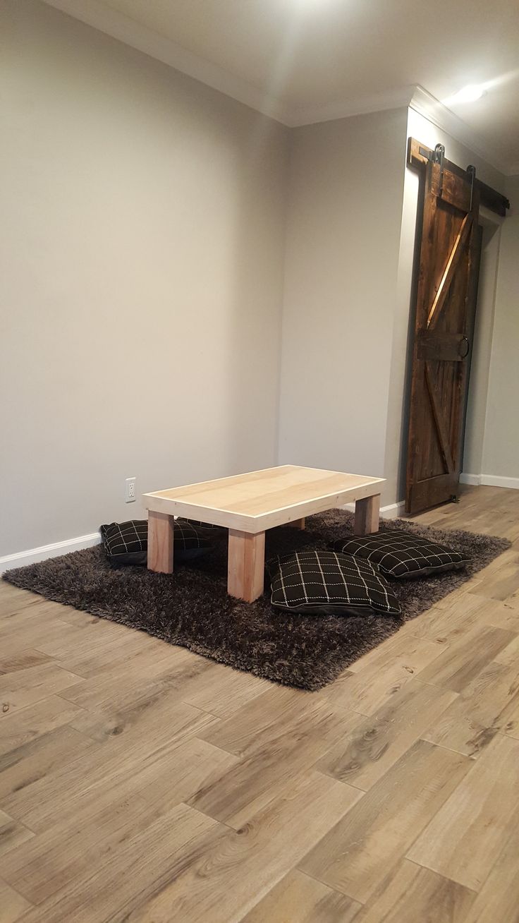 a living room with hard wood flooring and a wooden table on the rug in front of it