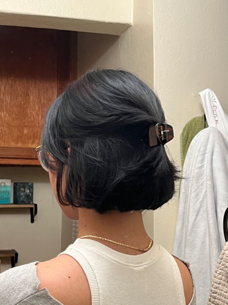 a woman with black hair is looking in the mirror