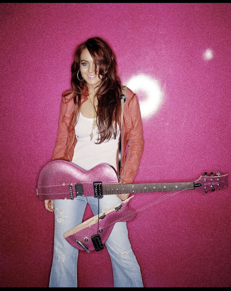 a woman holding a pink guitar in her hands