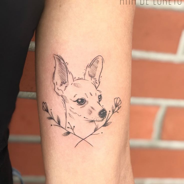 a small dog tattoo on the left inner arm and lower arm, with flowers in it