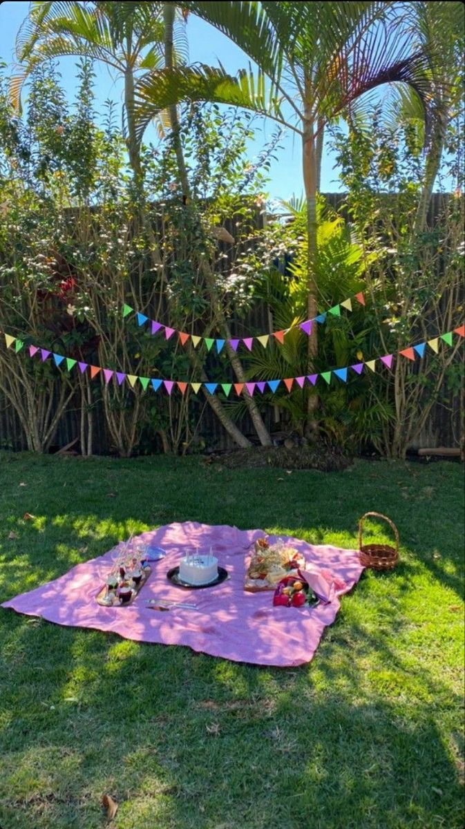 a picnic blanket on the grass with food and drinks laid out in front of it