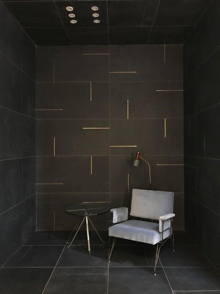 a chair and table in a room with black tiles on the floor, walls and ceiling