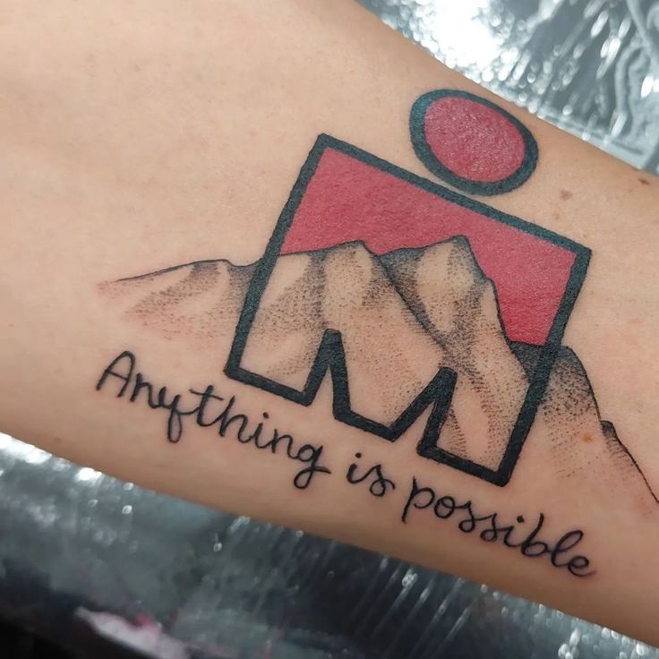 a tattoo that says anything is possible on someone's arm with mountains in the background