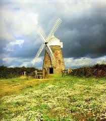 a windmill sitting on top of a lush green field