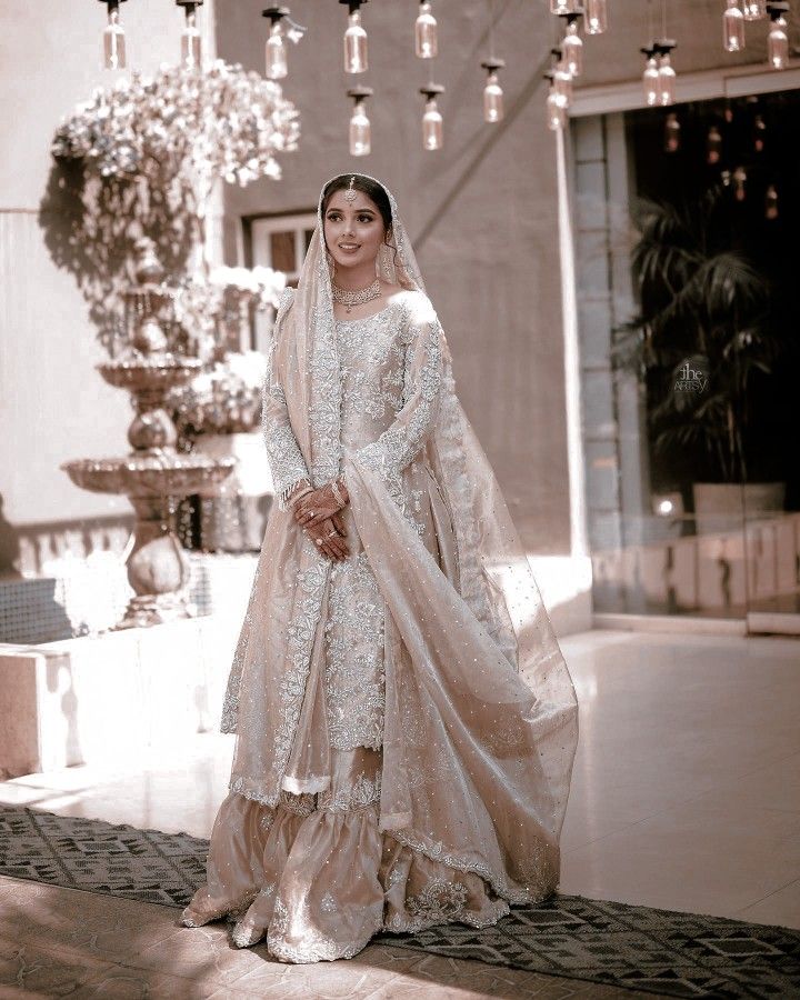 a woman in a white dress and veil posing for a photo with chandelier hanging from the ceiling