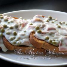 a white plate topped with two pieces of bread covered in meat and cheese toppings