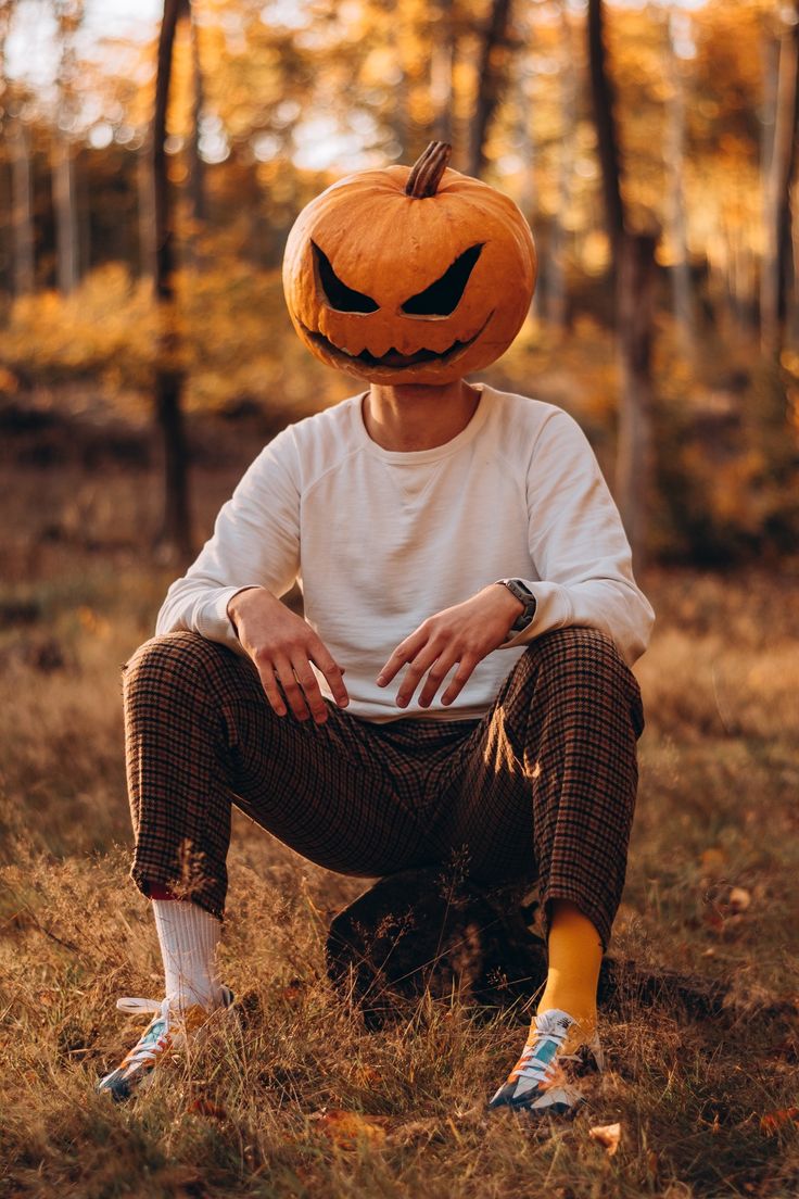 a man sitting in the grass wearing a pumpkin hat