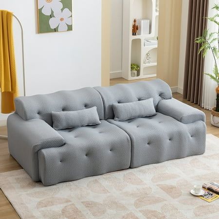 a grey couch sitting on top of a white rug