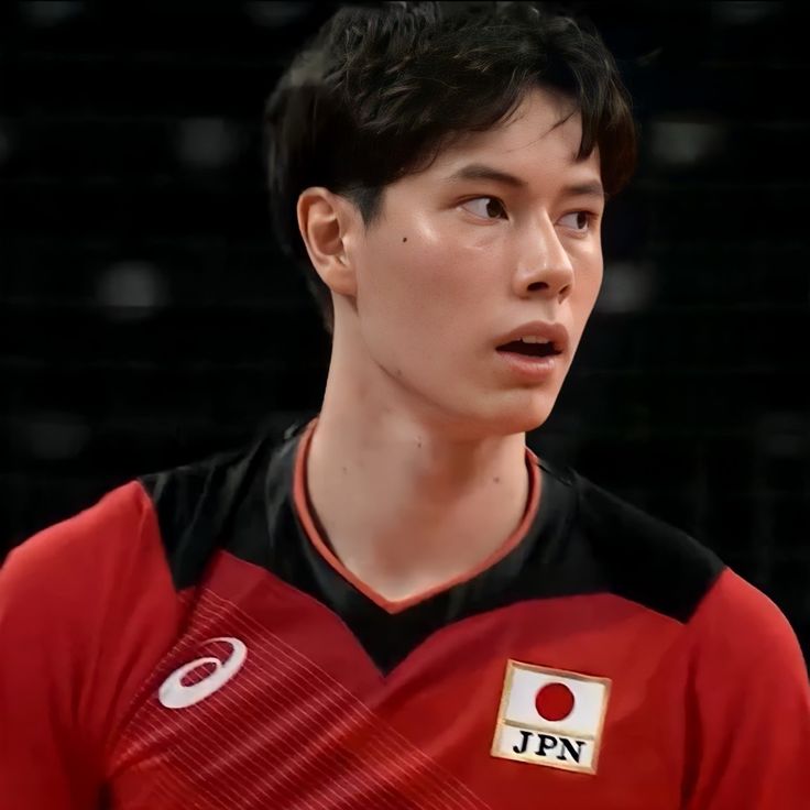 a young man in a red and black uniform looking at the camera with an intense look on his face