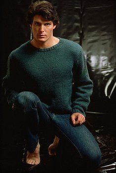 a young man in a green sweater is sitting on a black chair and posing for the camera