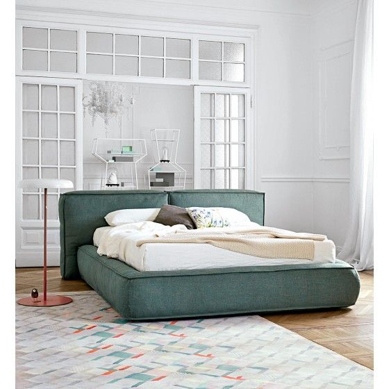 a large bed sitting on top of a hard wood floor next to a white wall