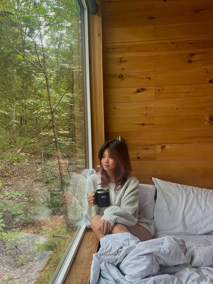 a woman sitting in bed looking out the window