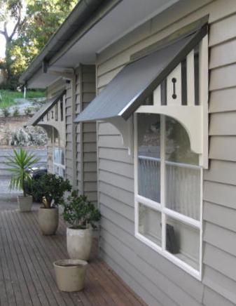 an outside view of a house with potted plants on the front porch and awning