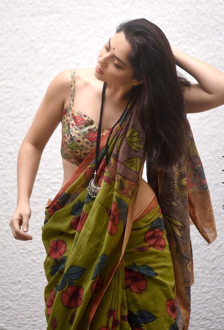 a woman with long hair wearing a green sari and holding her hands behind her head