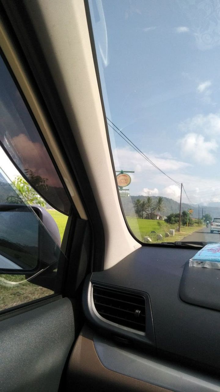 the rear view mirror of a car looking out at a grassy area in the distance