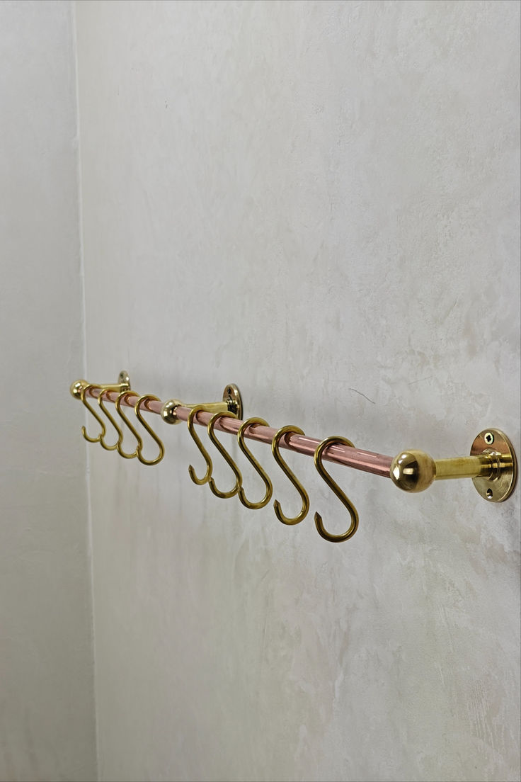 five hooks hang on the side of a white wall