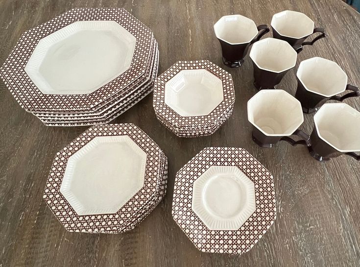 a table topped with plates and cups on top of a wooden table covered in dishes