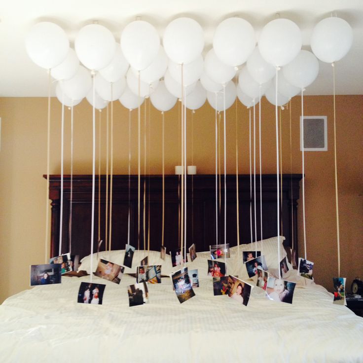 balloons are hanging from the ceiling above a bed with pictures and photos attached to it