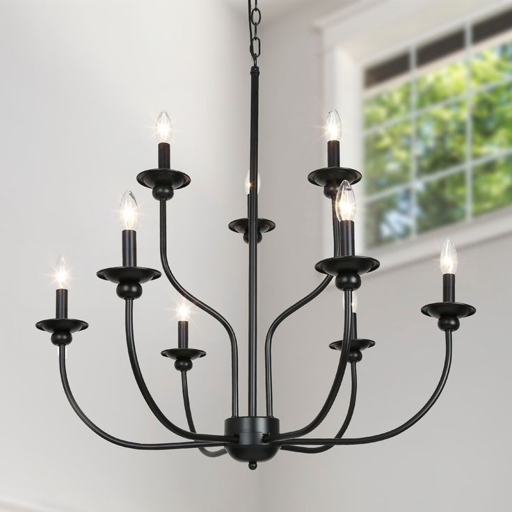 a black chandelier with six lights hanging from it's center, in front of a window