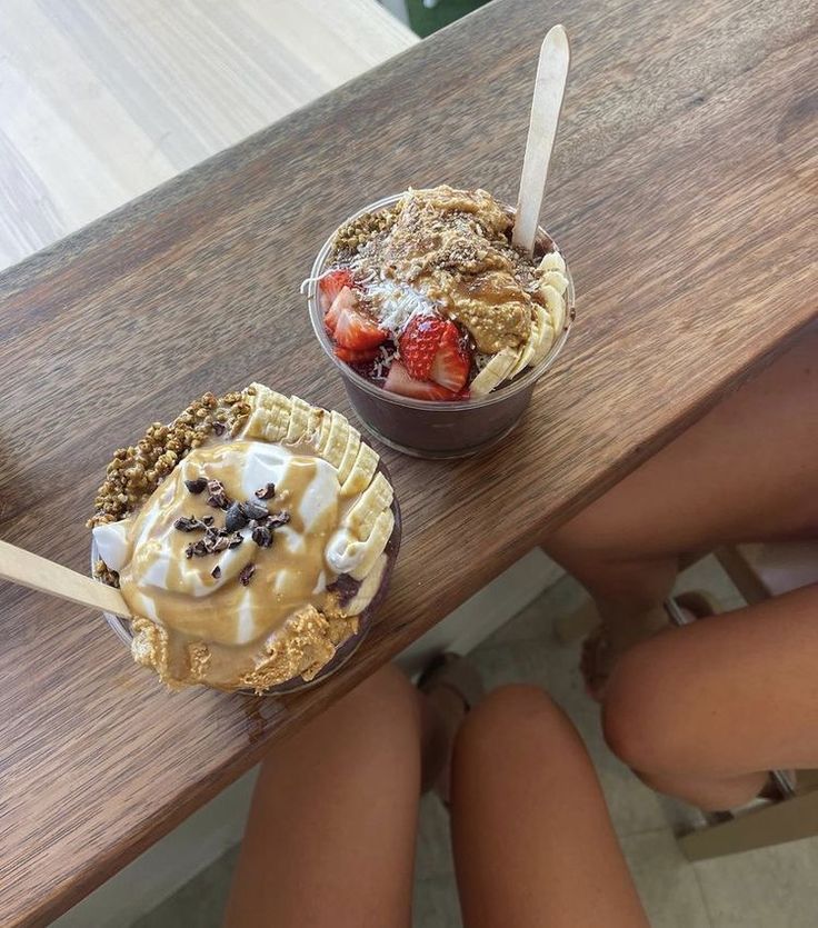 two desserts sitting on top of a wooden table with strawberries and ice cream