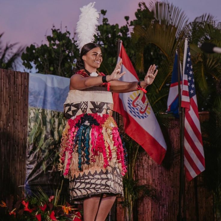 a woman in a native dress holding two flags