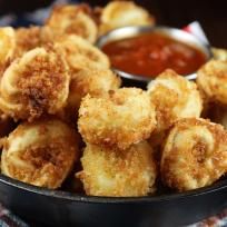 some fried food is in a black bowl on a checkered table cloth with dipping sauce