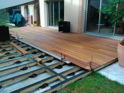 a wooden deck is being built in front of a house with large sliding glass doors