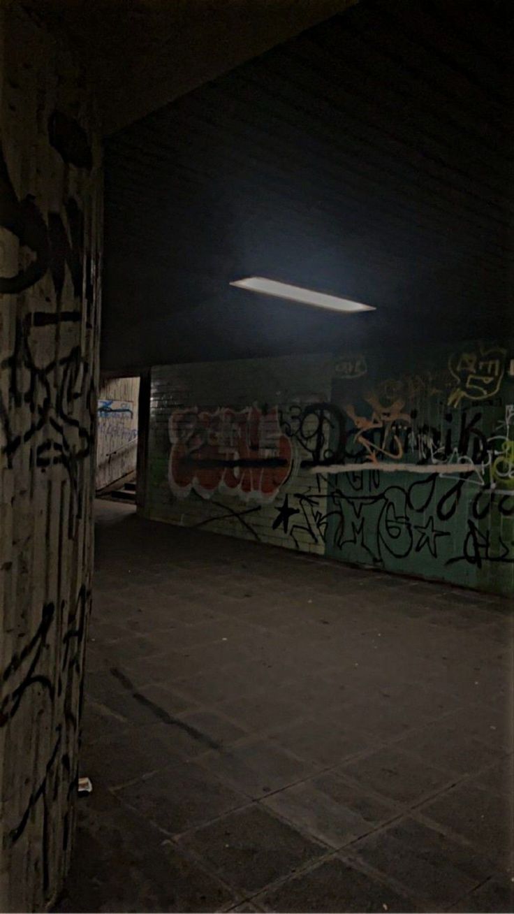 an empty parking garage with graffiti all over the walls and floor, under a street light