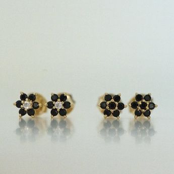 three pairs of black and white diamond studs on top of each other in yellow gold