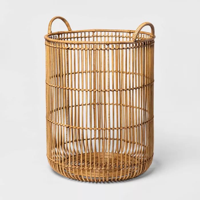 a round wicker basket with handles on the outside and inside, sitting on a white surface