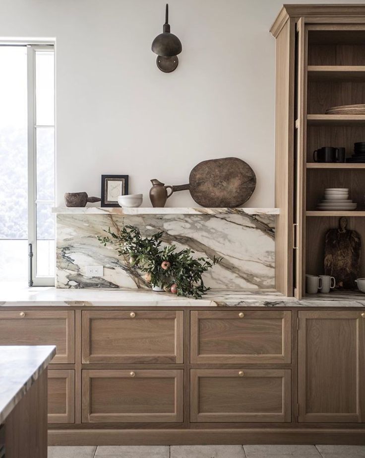 a kitchen with marble counter tops and wooden cabinets, along with pots on the wall