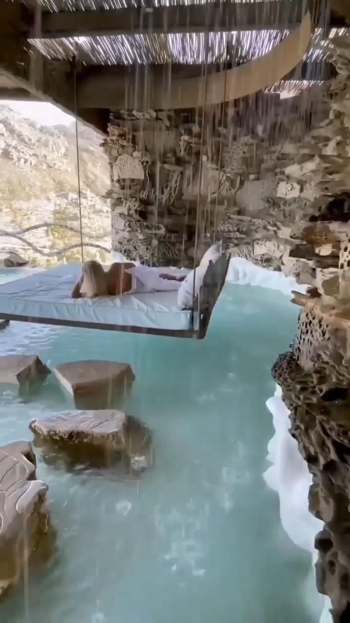 an indoor swimming pool in the middle of a desert area with rocks and water surrounding it