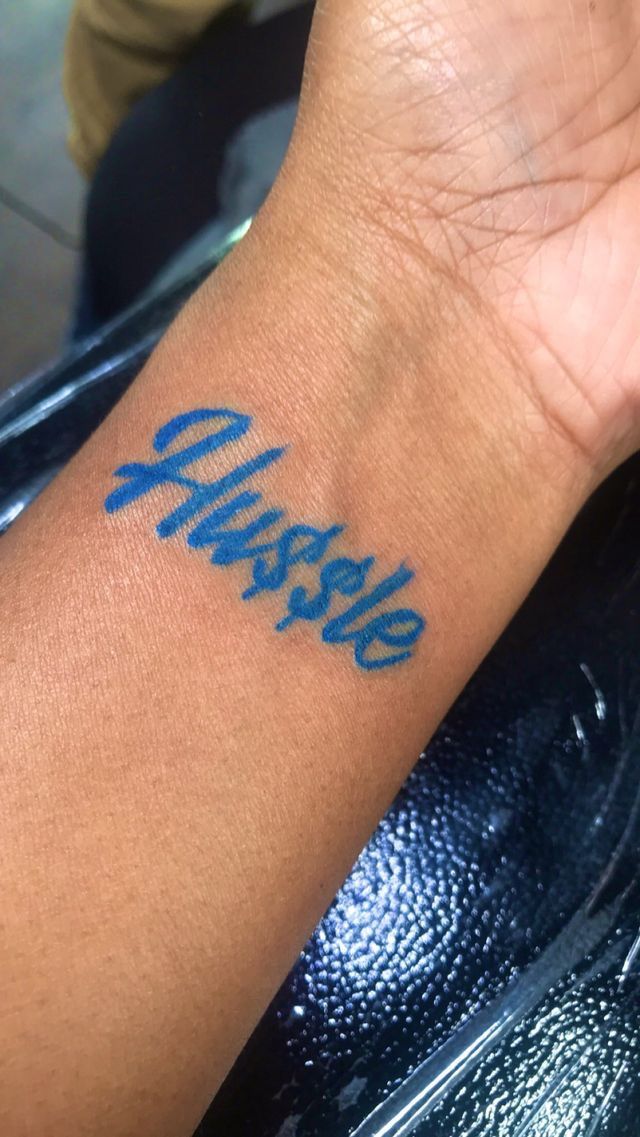 a person's arm with a blue tattoo on it that says, maybe in cursive writing