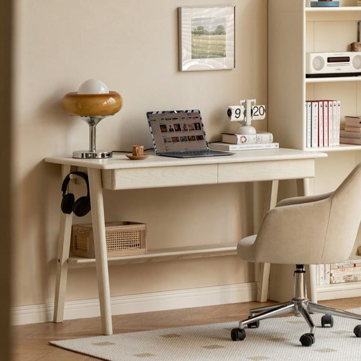 a desk with a laptop and headphones on it in front of a bookcase