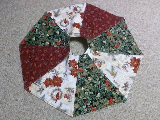 a circular piece of fabric with red and green flowers on it sitting on the floor