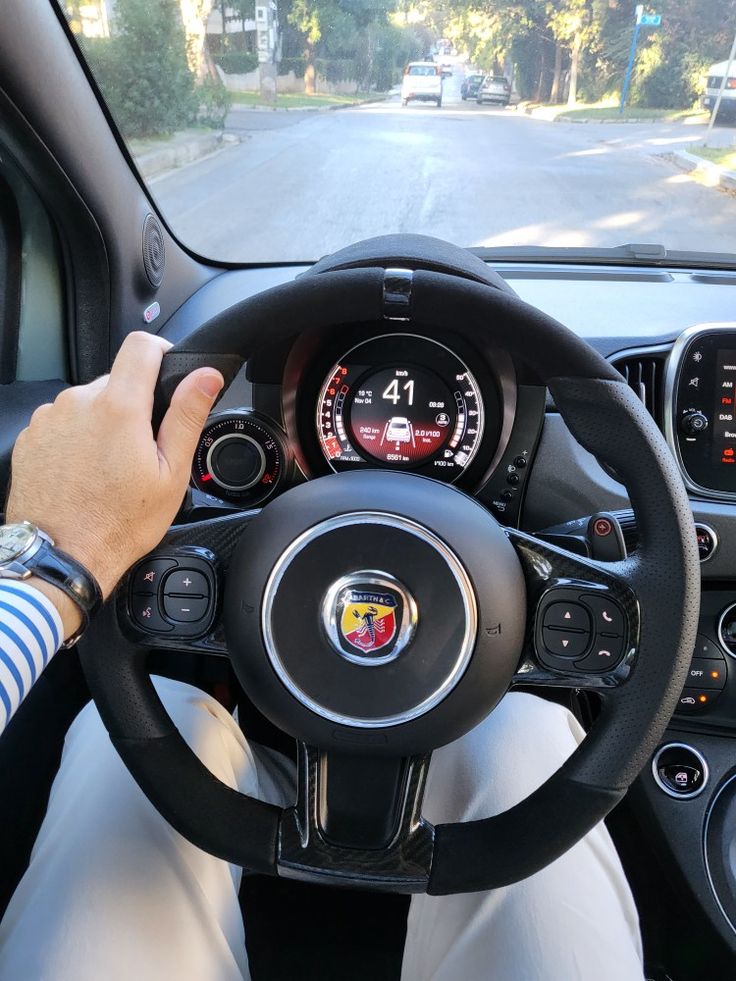 a person driving a car on the road with their hands on the steering wheel and dashboard