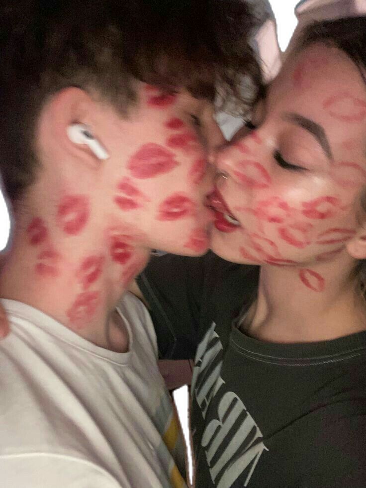 two people are kissing with their faces covered in red lipstick on the cheek and one person has his eyes closed