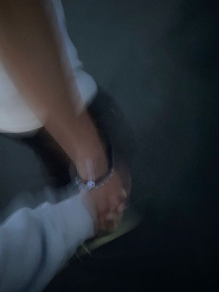 a blurry image of two people holding each other's hands while standing in the dark