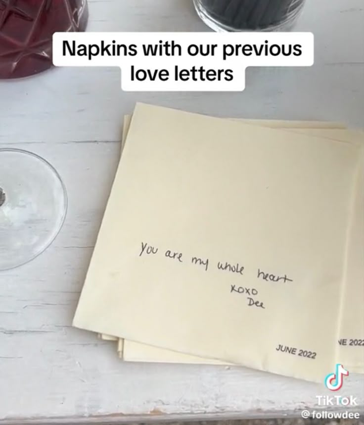 an envelope with writing on it sitting next to some wine glasses