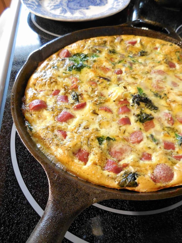 an omelet with ham and spinach in a skillet on the stove