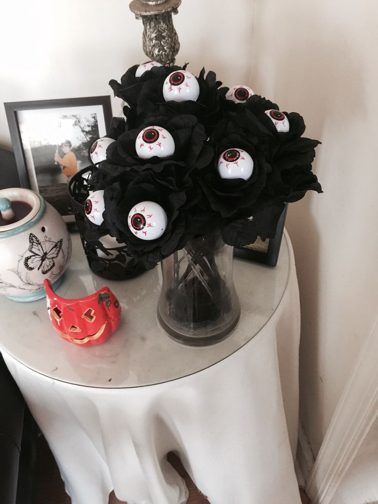 there is a vase with black flowers on it and some scary eyes in the center