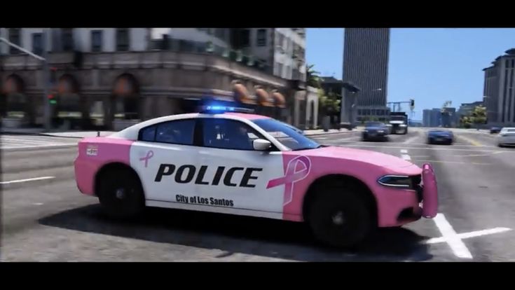 a pink police car driving down a street next to tall buildings