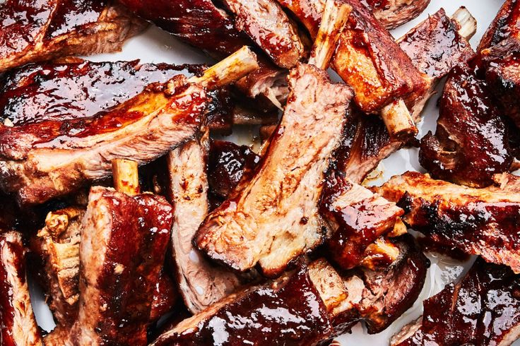 barbecue ribs with bbq sauce on a white plate ready to be cooked in the oven