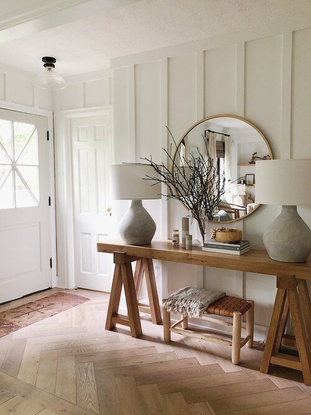 a table with two vases sitting on top of it next to a mirror and lamp